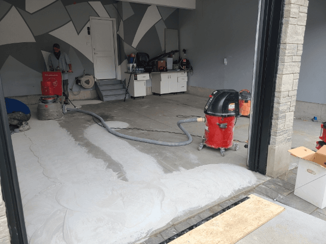Worn concrete garage floor being ground and resurfaced in a Kitchener, Ontario home